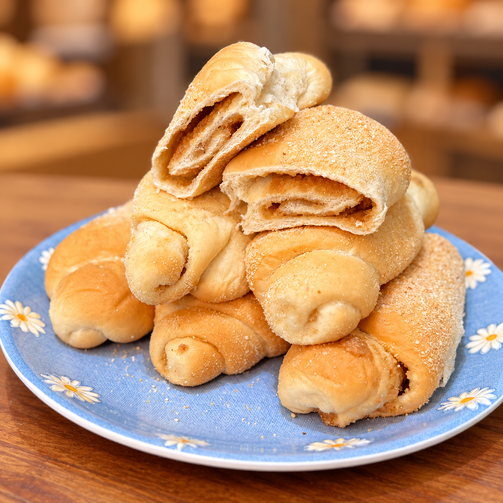 Filipino Spanish bread rolls with sweet filling on a blue floral plate